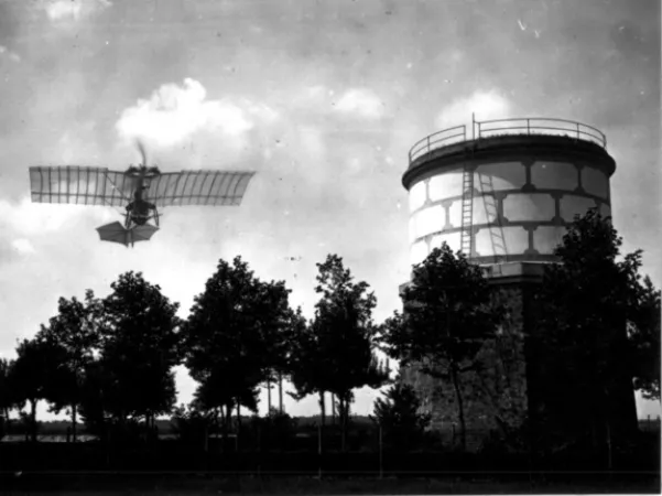 Black and white photograph showing a Santos-Dumont Demoiselle, an early aircraft with an open frame, in the sky above some trees and near a water tower.
