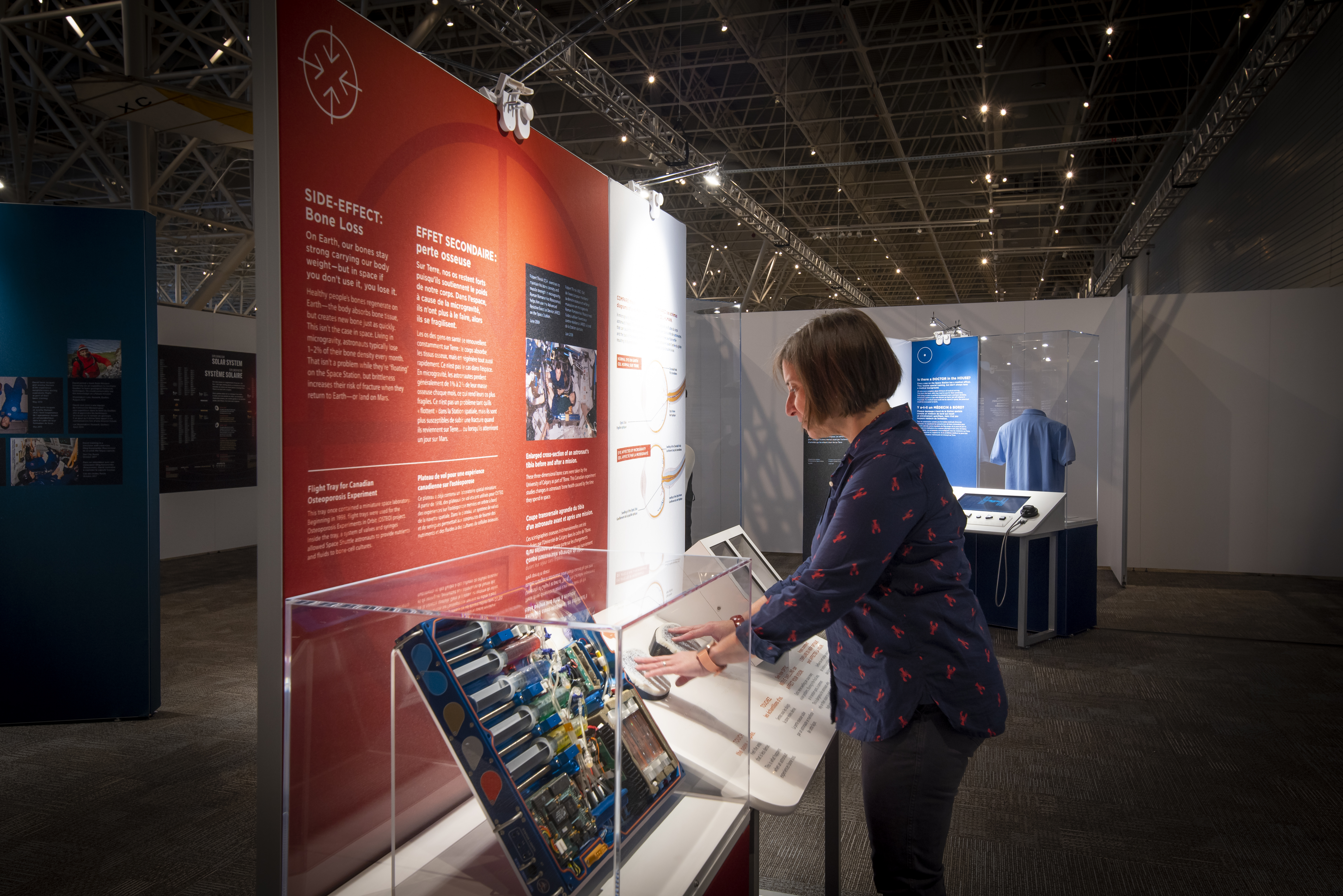 A woman stands in front of an exhibition panel inside the Canada Aviation and Space Museum.