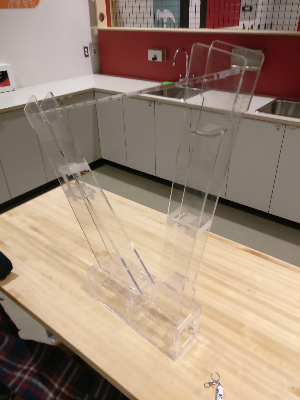 Un cadre en plastique transparent en forme de harpe repose sur une table.