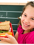 a young girl showing her lunch box with a sandwich