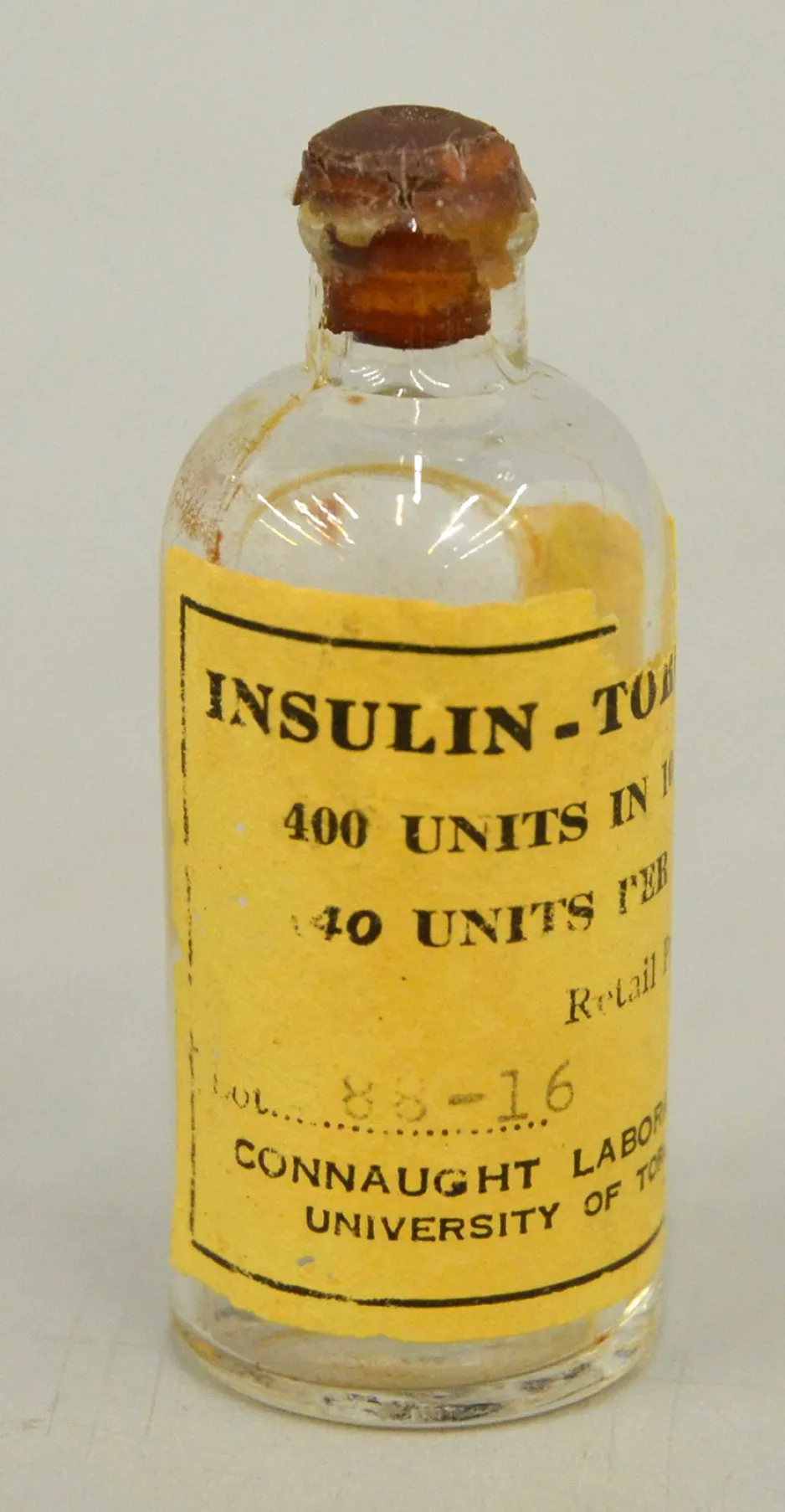 Petit flacon de verre muni d’une étiquette jaune vif sur laquelle le mot « Insulin » est clairement visible en lettre noires. Les mots « 400 units, 40 units » sont partiellement visibles dans le haut de l’étiquette et la mention « Connaught Laboratory, University of Toronto » est partiellement visible dans le bas de l’étiquette. 