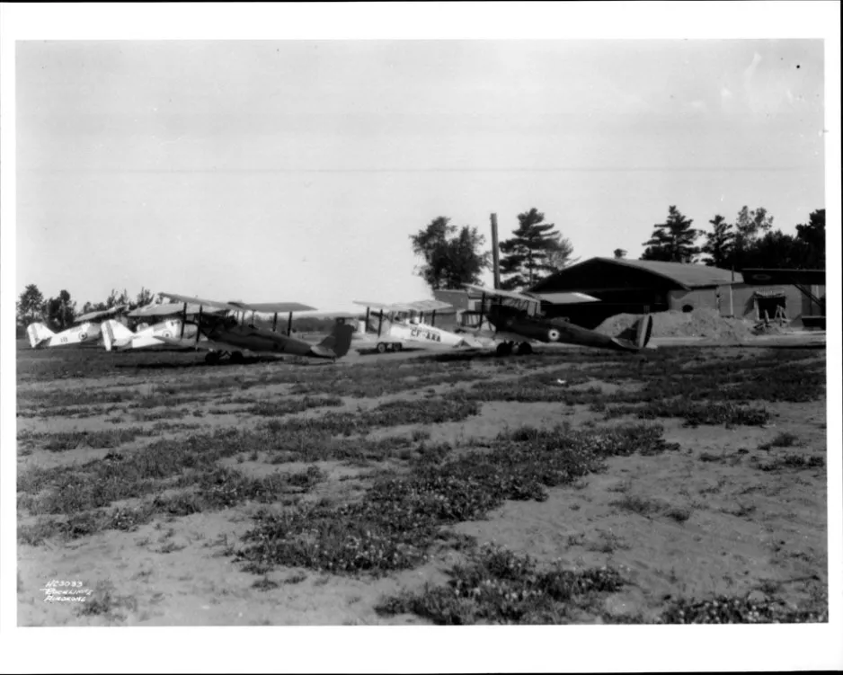 A lineup of period civilian and RCAF aircraft parked in front of an old hangar at Rockcliffe
