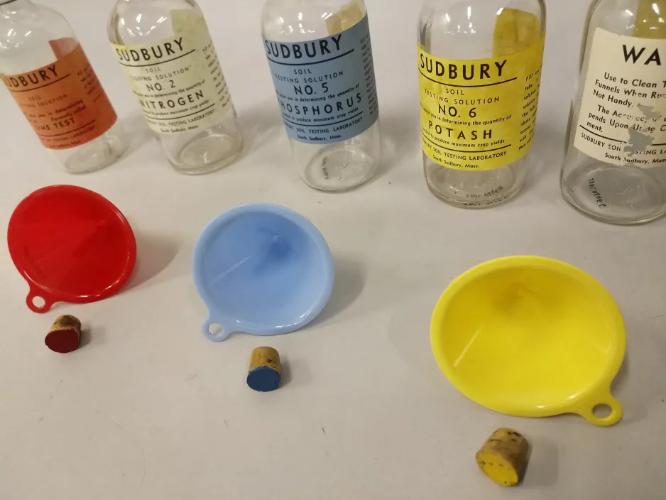 Empty bottles that were once filled with chemicals, colour-coordinated funnels, and test tube stoppers.