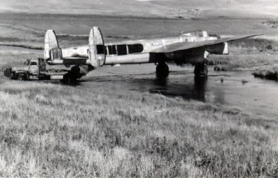This photo shows the Lancaster bomber that would later be dedicated to Bazalgette crossing a river. The bomber shows clear signs of disrepair. 