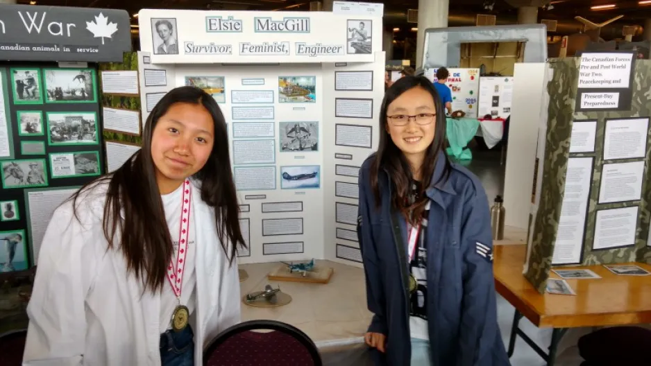 Two young girls stand in front of their research display about Elsie MacGill.