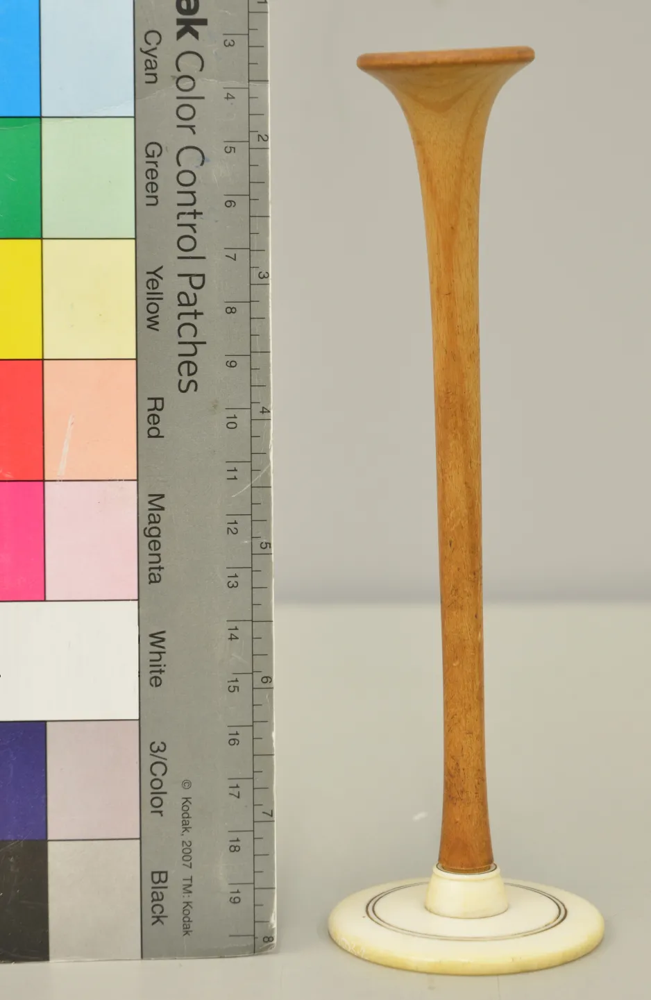 Stéthoscope délicat fabriqué à partir d’une étroite pièce de bois creuse. Il est en forme de cloche concave à une extrémité, et est fixé à un disque plat en os ou en ivoire, à l’autre extrémité.