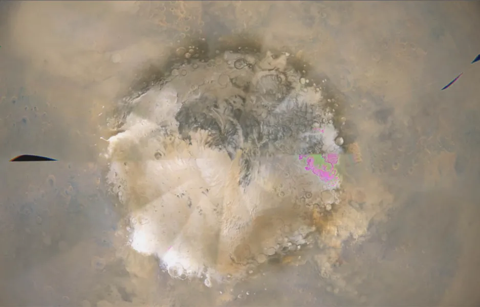 An aerial photo of a pole of Mars; white and tan splotch on a grey-brown background 