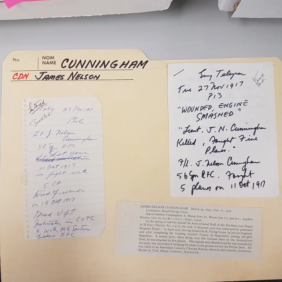 A colour photograph shows a file folder with the title “Cunningham. Cdn. James Nelson.”  Three slips of paper are visible, including one handwritten note with the following words in capital letters “WOUNDED, ENGINE SMASHED.”