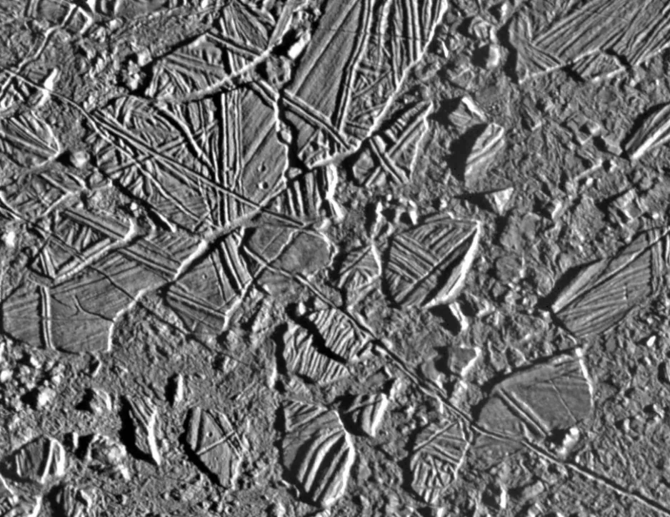 Image en tons de gris montrant des segments de glace de forme irrégulière, avec différentes surfaces striées et linéaires entourées de régions plus lisses à faible relief.