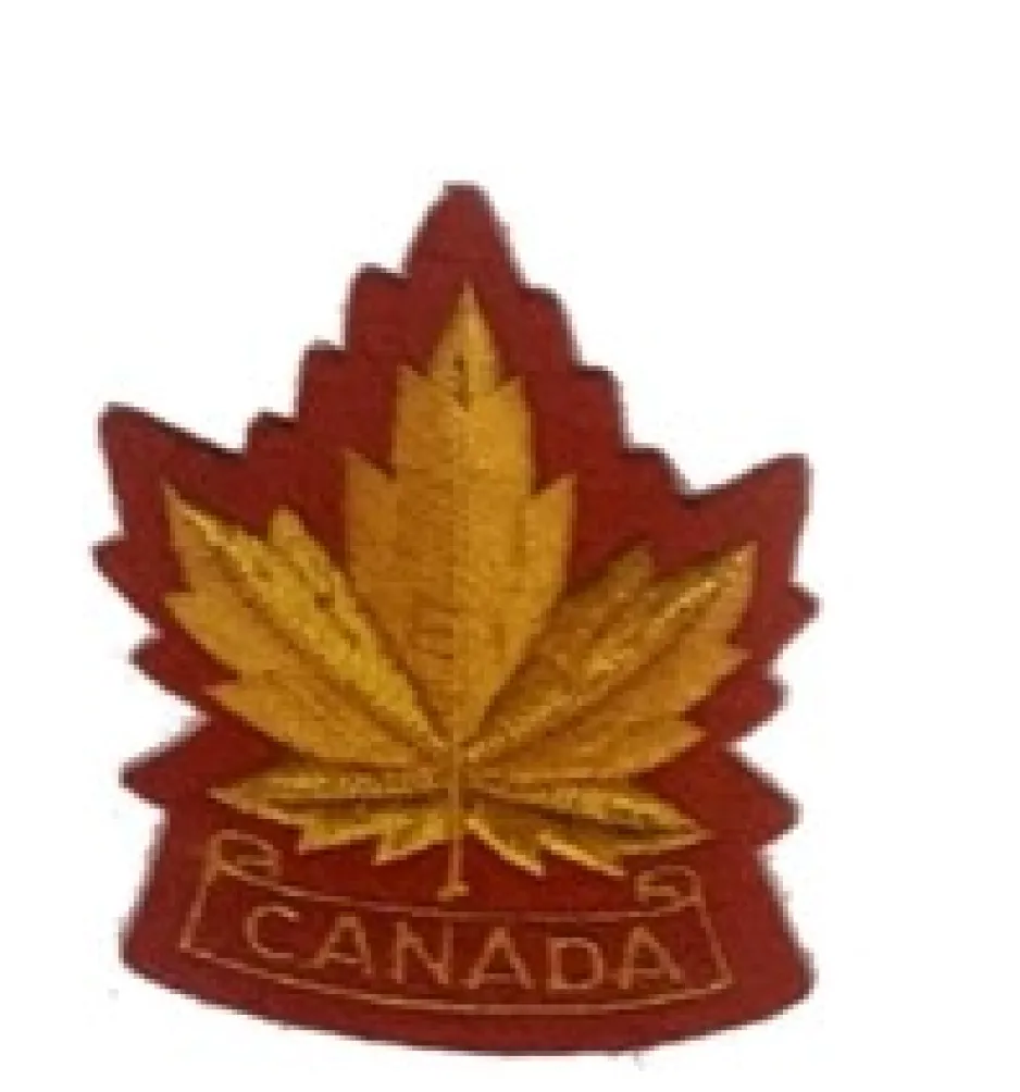 Écusson scout rouge et or avec une feuille d’érable au centre et une bannière CANADA en dessous.