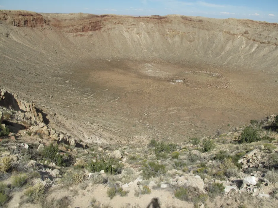 View of kilometer-wide hole in the ground, with rock layering visible around the rim.