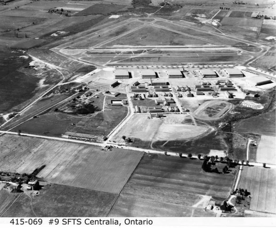 Une image en noir et blanc montre une vue aérienne d’une base de l’ARC. On voit des bâtiments ainsi que la bande d’atterrissage de la base entourée de terres agricoles.