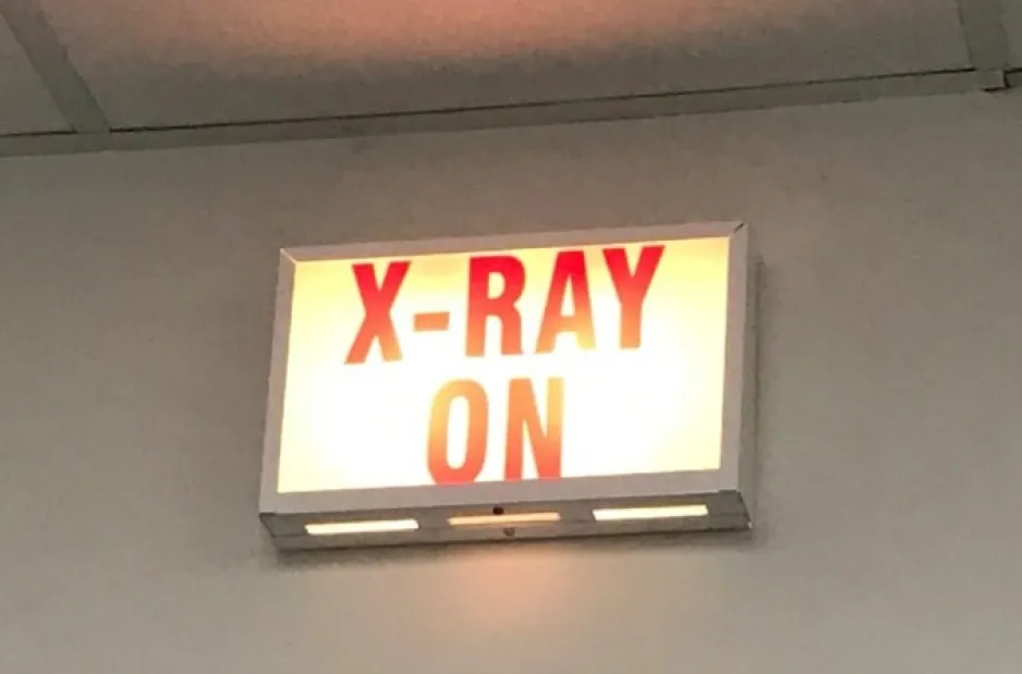 A backlit sign with red lettering and a white background, reading “X-RAY ON.”