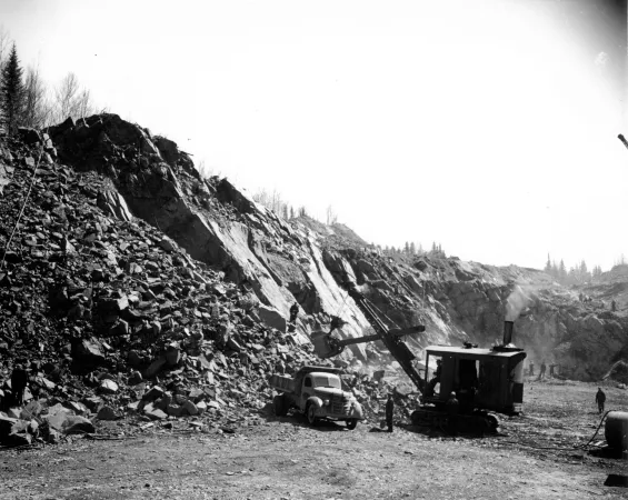 Des travailleurs chargent le minerai de fer qui a été extrait d’une colline entière du même gisement dans l’est du Canada.