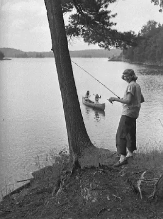 Femme avec une canne à pêche à coté d`un lac 