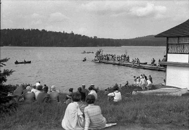 People on shore watching boating on lake