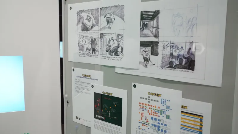 An exhibition panel shows a print out of a video game development schedule, with storyboard sketches of a hockey video game above it.