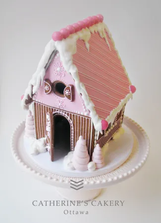 A pink gingerbread house sites on top of a cake tray.