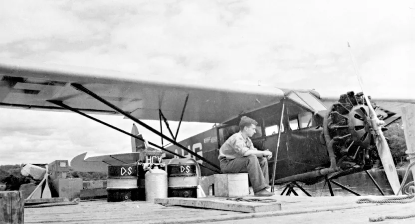Ken Molson sitting on a dock near a seaplane