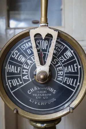 A close-up view of an old brass dial, which served as the engine room’s telegraph.