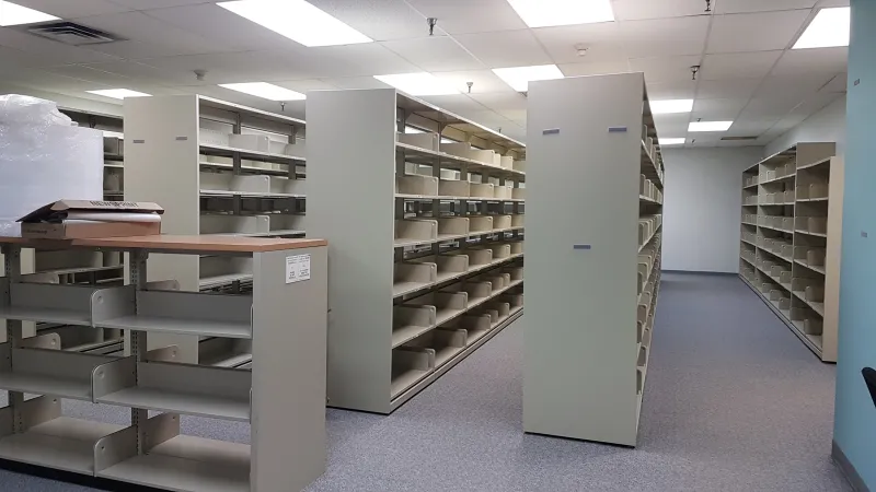 Photo shows four rows of empty shelves in the old 2380 Lancaster Library with some packing material visible
