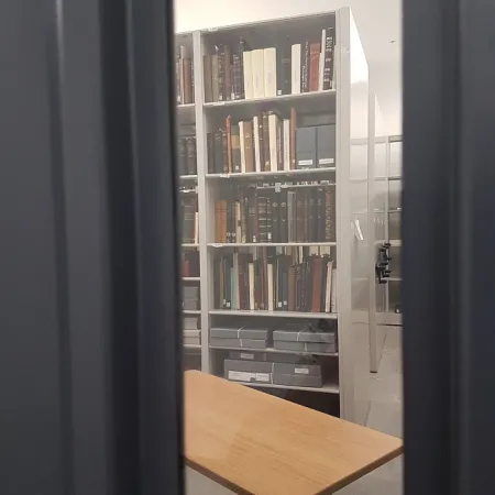 Photo shows a shelf in the new Ingenium Centre rare books room through the glass of a window in the door