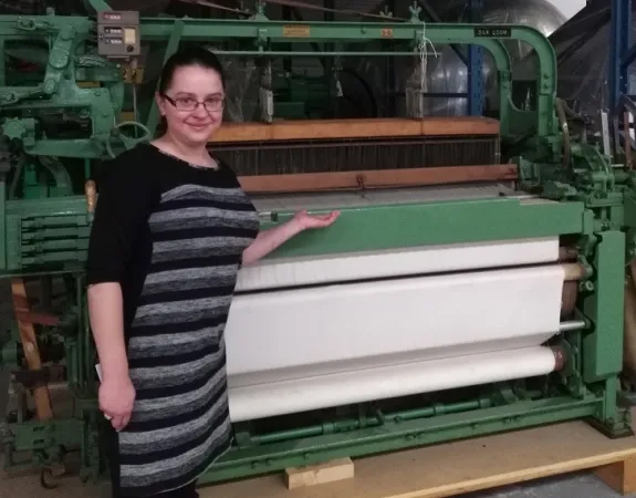 A large, green industrial loom that has a number of cranks and wheels.