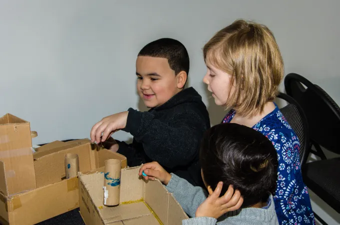 Three children designing and building their own cardboard games