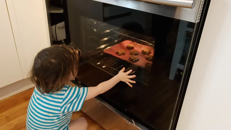 Un jeune enfant regarde cuire les biscuits dans un four.