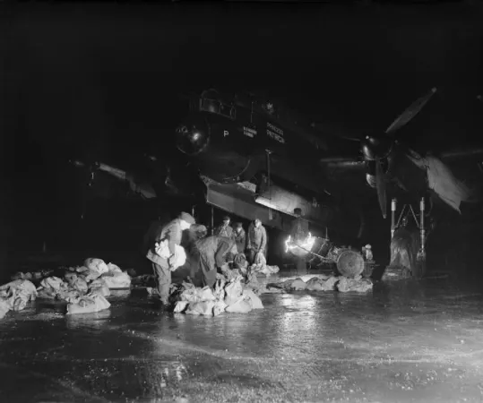 Personnel au sol chargeant des approvisionnements dans la soute à bombes d'un Avro Lancaster du 514e escadron de la Royal Air Force au cours de l'opération Manna, le largage de nourriture à la population néerlandaise affamée. 