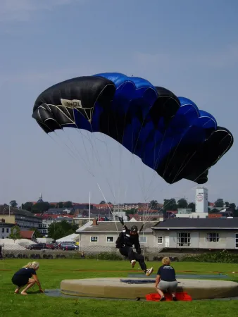 Le Danois Jan Bo Kristensen effectuant un atterrissage de précision avec un parachute-voile lors d’une compétition nationale organisée par la Dansk Faldskærms Union, Randers, Danemark, août 2005. Wikipédia.