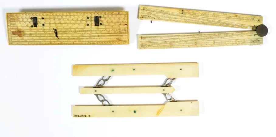 Three yellow-brown tools sit on a white background: a scale, a protractor, and a ruler. 