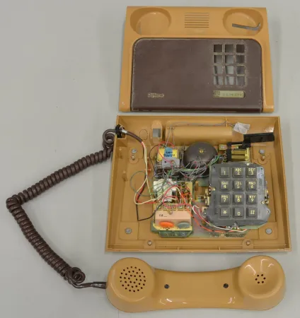 Un téléphone brun a été partiellement démonté; son plateau ayant été retiré, on peut voir ses composants internes.