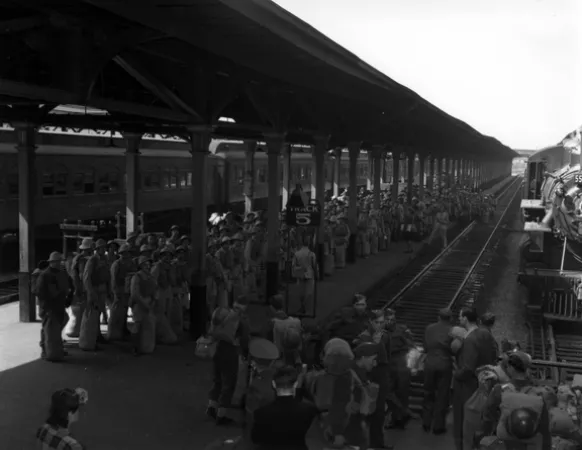 L’image est une photo noir et blanc montrant une foule nombreuse de soldats sur un quai de la gare Bonaventure, à Montréal. 