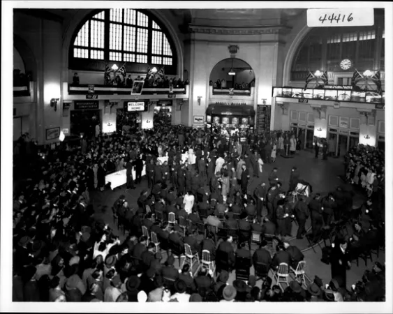 L’image est une photo noir et blanc montrant une foule de militaires dans une gare, à leur retour au pays. 