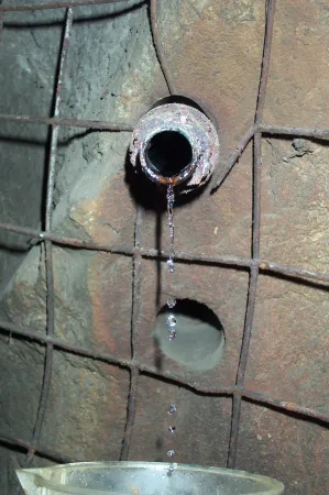 Water drips from a pipe in the rock underground.