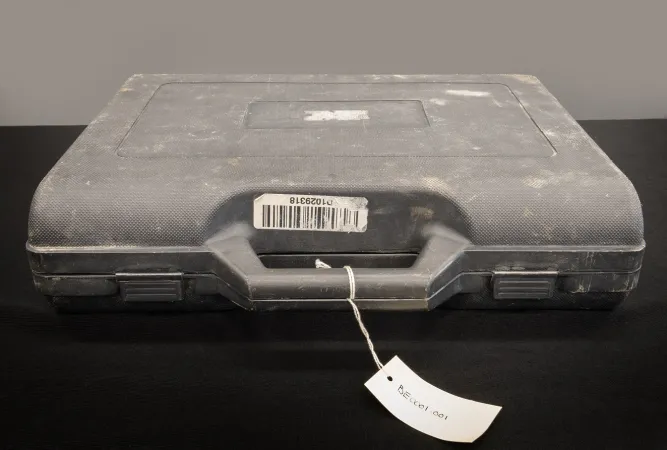 A dusty dark grey rectangular kit sits on a dark surface.