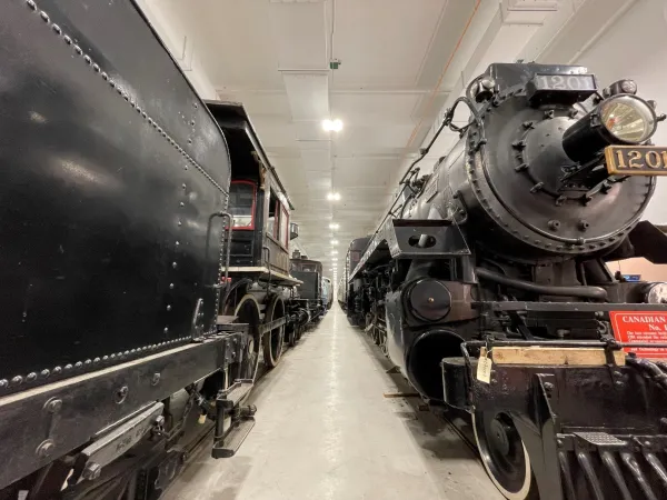 An image looking down the centre of a large room with two rows of locomotive and rolling stock artifacts. 