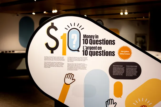 Un panneau intitulé « L’argent en 10 questions » présente l’exposition à l’aide de graphiques jaunes et bleus.