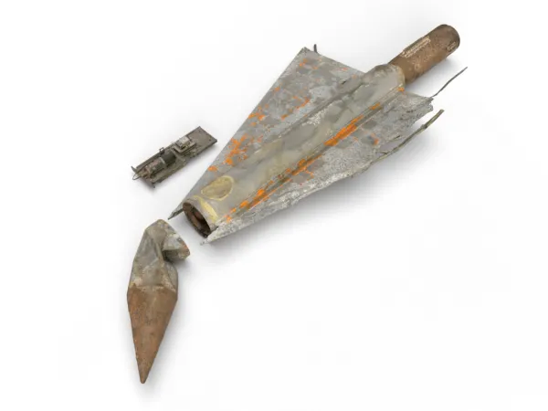Un modèle bosselé et endommagé d’un avion d’essai, rouillé avec des taches orange et grises. 