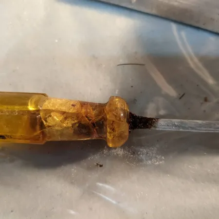 A close-up view of the shattered yellow plastic handle of a screwdriver. 