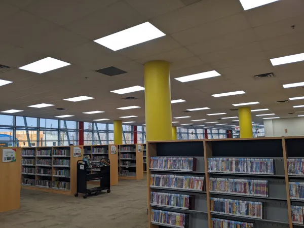 Rows of bookshelves with round yellow poles connecting them to the ceiling. 