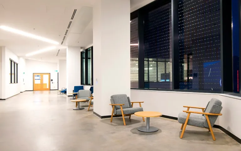 Un couloir lumineux avec de grandes fenêtres, de hauts plafonds et des fauteuils
