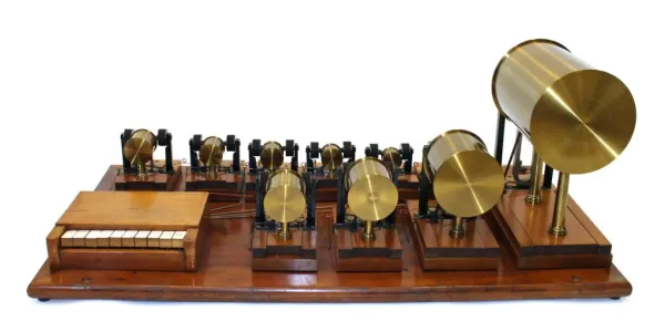 Instrument de table comprenant un petit clavier de 10 touches en bois et ivoire et 10 résonateurs cylindriques en laiton. Le tout est monté sur une base en bois.