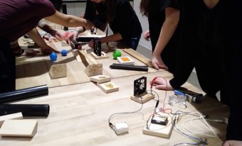 Un groupe d'étudiants travaille à une table en utilisant une série de fils et de matériaux pour réaliser des expériences. 