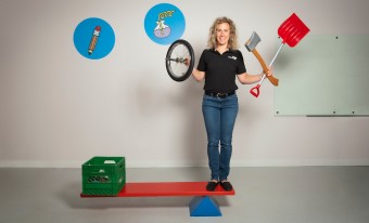 A museum employee showing the functionality of a simple machine while holding other simple machines