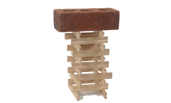 Des bâtons de bois sont empilés, deux par couche et en alternant la direction dans chaque couche pour former une tour à base carrée avec un centre creux. Une brique est posée au sommet de la tour.