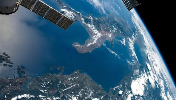 The planet Earth from nearby space. A satellite can be seen in the corner of the photo