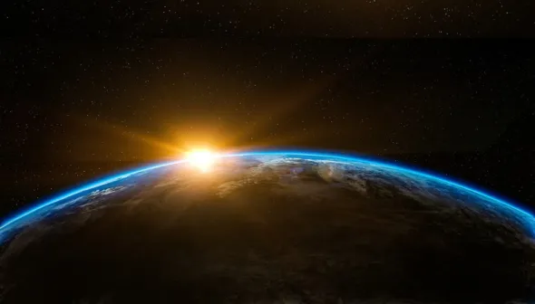 Vue d'environ un tiers de la Terre depuis l'espace. Le Soleil est partiellement visible derrière la planète.