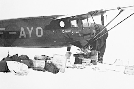 Supplies on snow in front of Dominion Skyways airplane